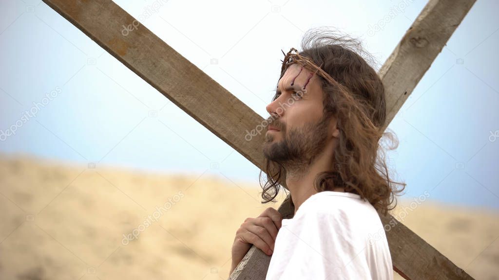 Jesus Christ with crown of thorns carrying cross, praying to God for sinners