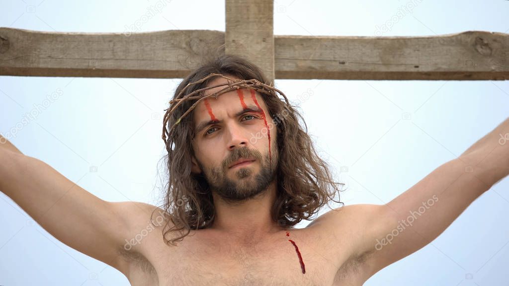 Jesus suffering nailed to cross, looking into camera, sacrifice for sinners