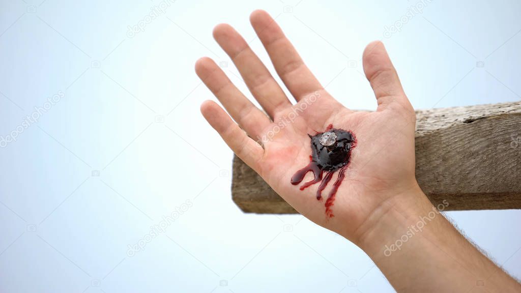 Jesus hand nailed to cross, clotted blood on wound, reenactment of crucifixion