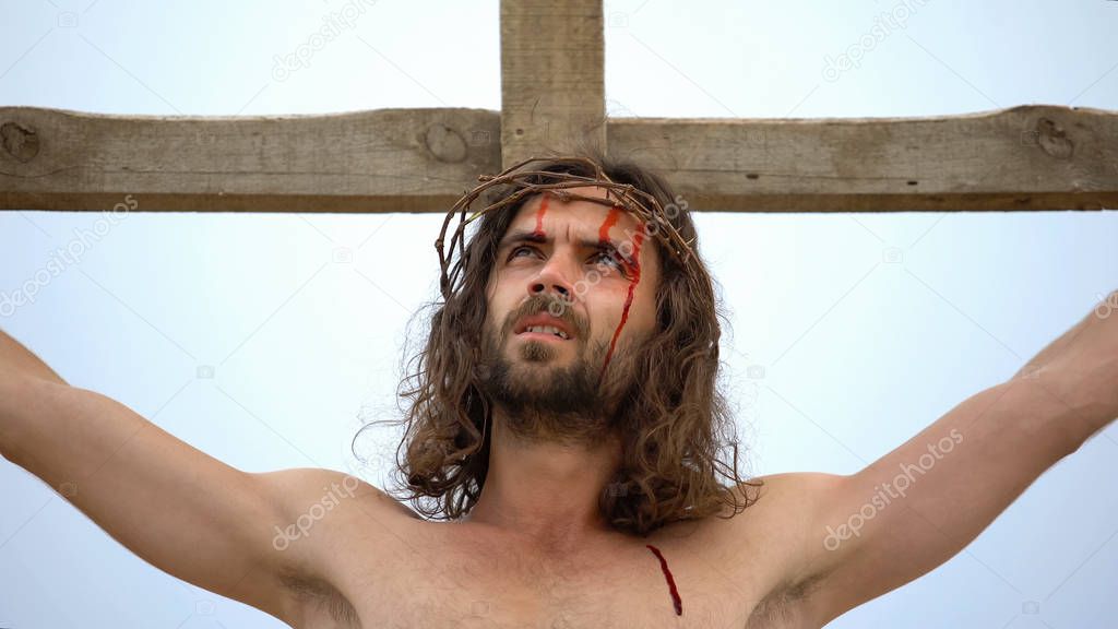 Jesus nailed to cross looking to sky, blood drops flowing down face, crucifixion