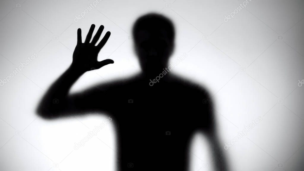 Man silhouette touching glass wall, searching way out, trapped victim, danger