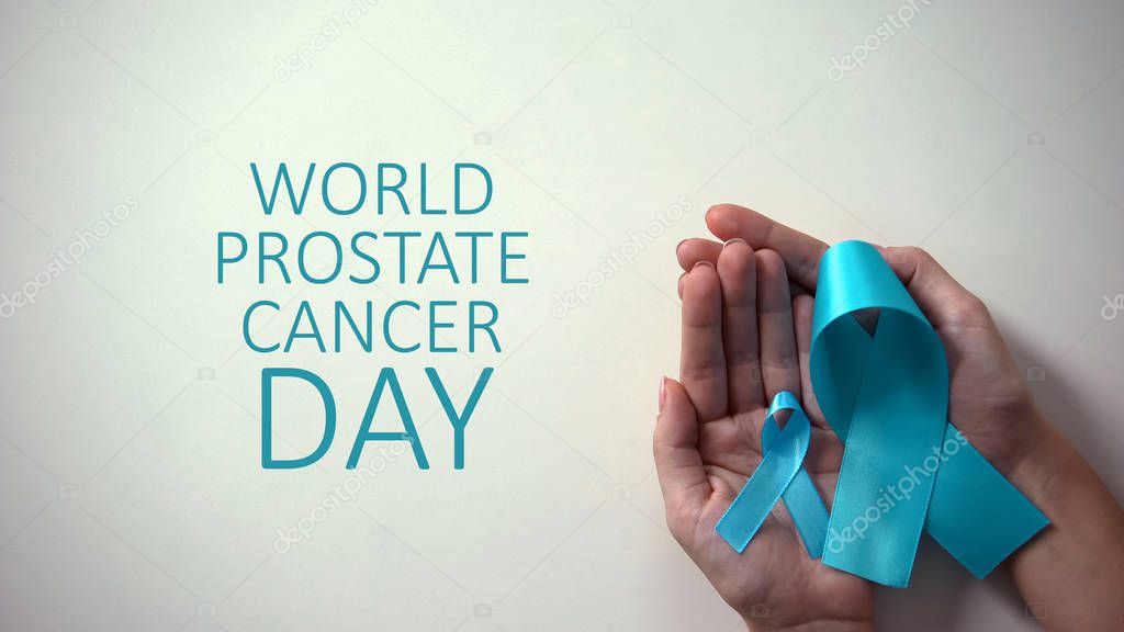 World prostate cancer day inscription, big and little blue ribbons in hands
