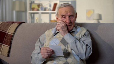 Ağlayan yaşlı adam fotoğrafa bakıyor, eski kayıp arkadaşını, anılarını hatırlıyor