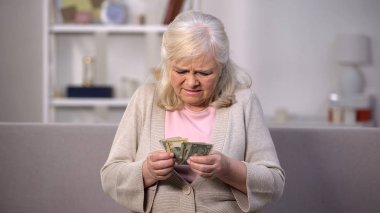 Üzgün yaşlı kadın dolar sayma, düşük yaşam standardı, emeklilik yaşı artışı