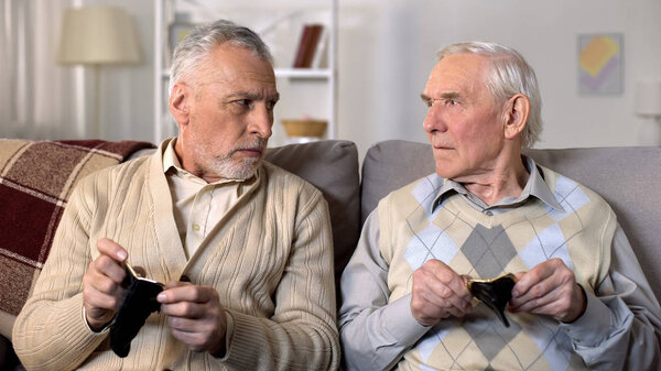 Unhappy senior men sitting on sofa holding empty wallets, social insecurity