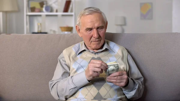 Hombre Viejo Deprimido Sentado Sofá Sosteniendo Billetes Dólares Inseguridad Social — Foto de Stock