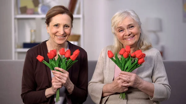 Весёлые Пожилые Женщины Смотрящие Камеру Отмечают День Матери Красными Тюльпанами — стоковое фото