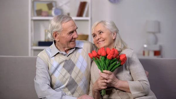 Пожилой Мужчина Обнимает Счастливую Женщину Кучей Тюльпанов Представляет Приветствие Внимание — стоковое фото
