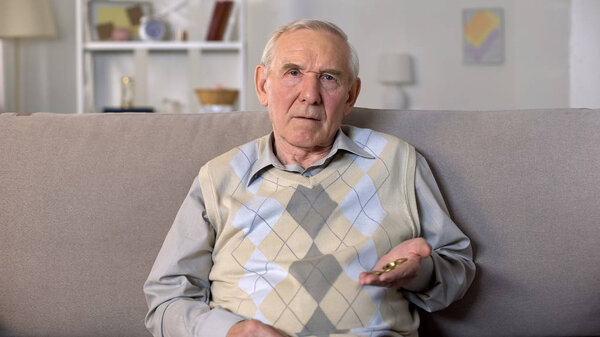 Old man counting coins hand looking camera, pension fund, poverty hopelessness