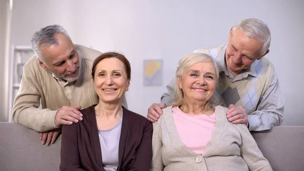 Счастливые Пожилые Мужчины Смотрят Зрелые Улыбающиеся Жены Сидя Диван Пенсионное — стоковое фото