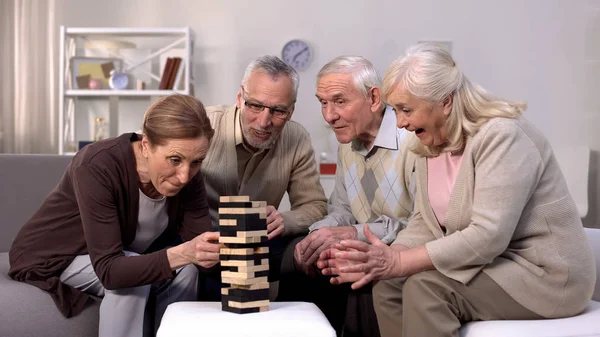 Elderly friends building tower from wooden cubes leisure time in nursing home