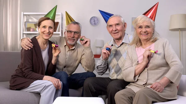 Lächelnde Ältere Gruppe Von Menschen Mit Partyhüten Die Kamera Haltend — Stockfoto