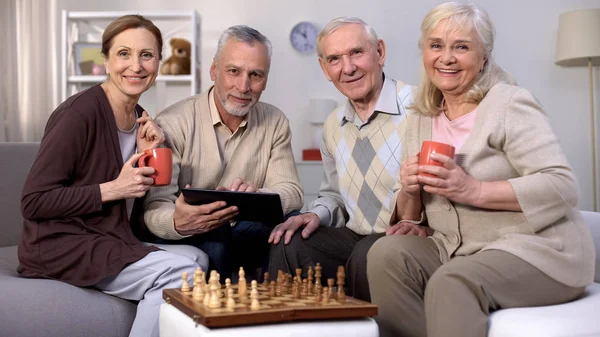 Fröhliche Reife Freunde Die Schachregeln Auf Dem Tablet Lesen Die — Stockfoto