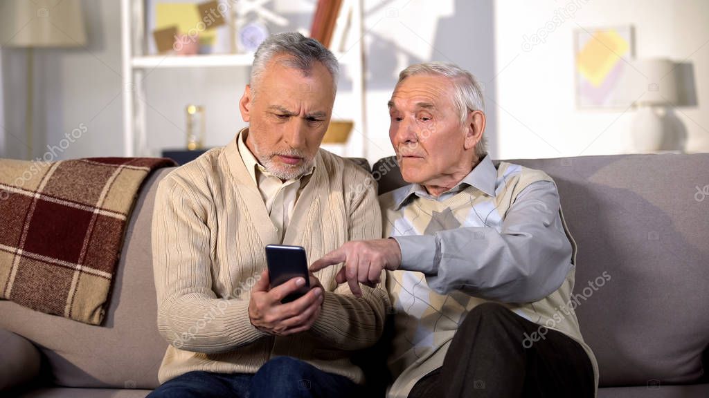 Two mature friends learning to use smartphone application, modern technology