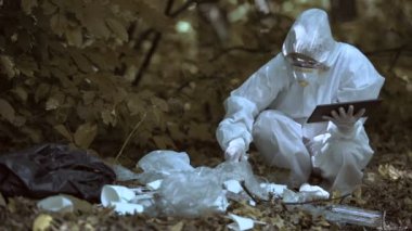 Laboratuvar araştırmacısı plastik atık ormanı analizi için tablete veri raporunu giriyor.