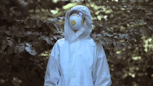 오염 된 숲 앞 플라스틱 매립지에서 있는 보호 복을 입고 있는 여자 — 비디오