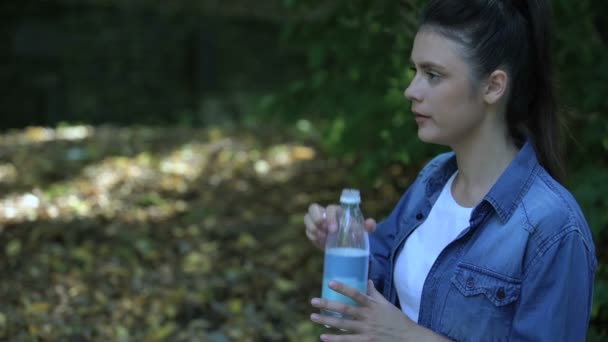 Gedachteloze vrouwelijke consument gooit waterfles in bos, plastic afval — Stockvideo