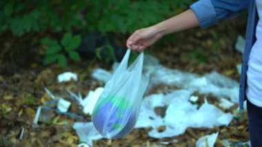 Gezegen oyuncağını plastik torbaya koyan dikkatsiz kadın çöp sahasında, geri dönüşüm