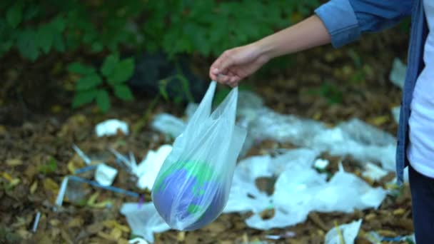 Небрежная женщина бросает игрушку планеты в пластиковый пакет на свалку, переработка — стоковое видео