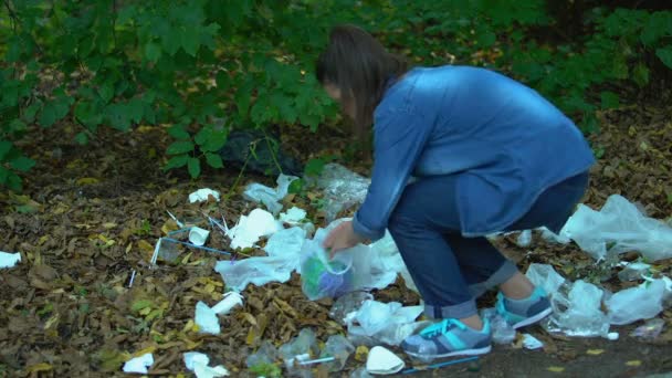 Caring young woman taking earth planet from plastic landfill forest, ecology — Stock Video