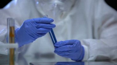 Zehirli laboratuvar çalışanı biyolojik tehlike sıvısıyla test tüpü gösteriyor. Virüs türü.