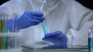Kimya laboratuarı asistanı zararlı bir işaret ve böcek ilacı içeren tüp gösteriyor.