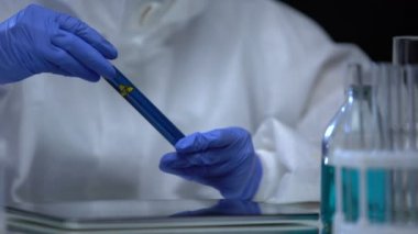 Bilim adamları deney tüpünü biyo-tehlike sıvısıyla inceleyip tablet üzerinde notlar alıyorlar.