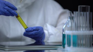 Yakıt laboratuarı asistanı tortu ve kalite kontrolü için test tüpünü petrolle inceliyor.