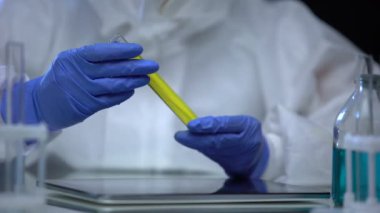 Koruyucu kıyafetli laboratuvar çalışanı yanıcı yakıt ve kontrol örneklerini araştırıyor.