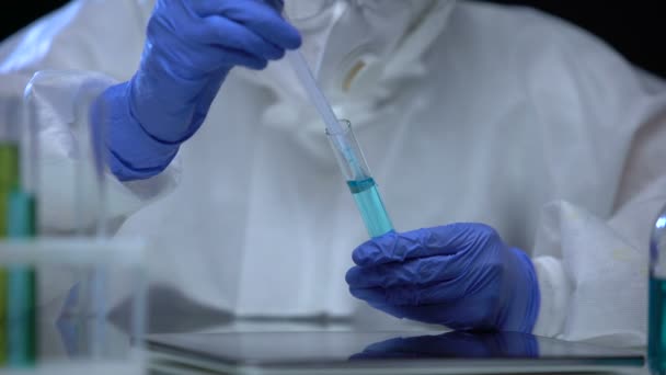 Trabajador de laboratorio en traje protector tomando muestra de tubo de ensayo con signo dañino — Vídeo de stock