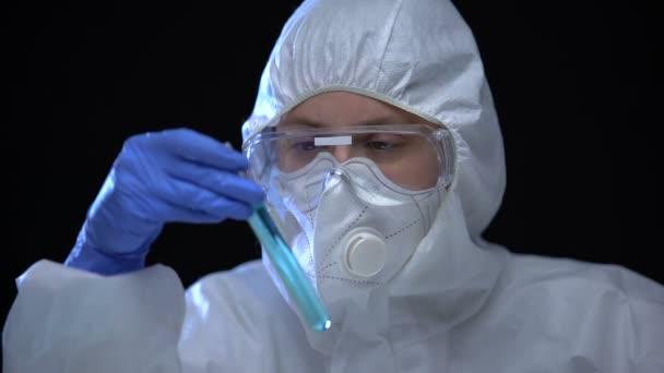 Trabajador de laboratorio tóxico estudiando líquido azul en tubo de ensayo con signo dañino — Vídeo de stock