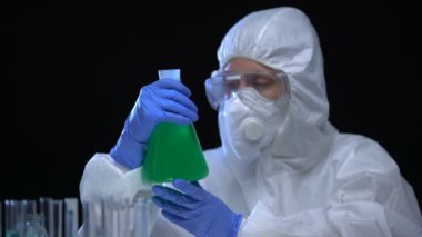 Yasadışı laboratuvar çalışanı elinde radyoaktif sıvı, su zehirlenmesi ve suç şişesi tutuyor.