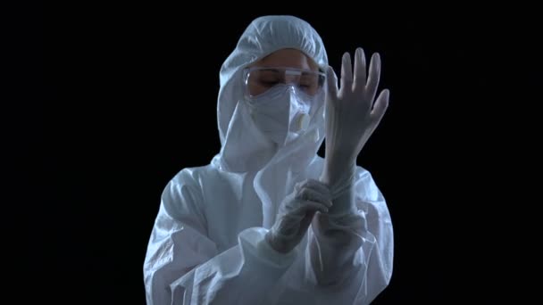 Koruyucu giysili kişi siyah arka plan ve toksinlere karşı lastik eldiven giyiyor. — Stok video