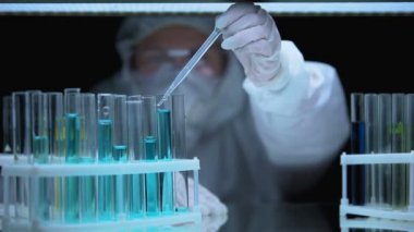 Düşüren bilim adamı deney tüpünden sıvı örneği alıyor, yasadışı deney.