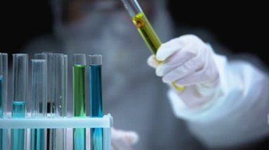 Araştırmacı test tüpünden ateş sembolü, uyarı işareti ve tehlike içeren sıvı ekliyor.