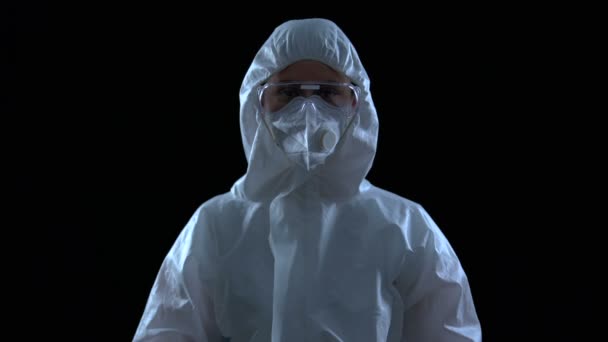 Женщина в защитном костюме и маске, пугающе поднимает руки, вирус распространяется — стоковое видео