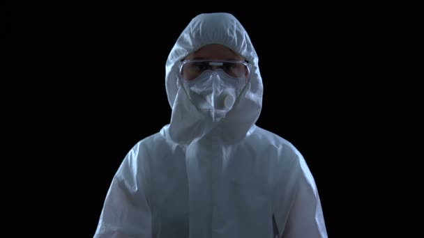 Lab werknemer in pak met generieke waarschuwing symbool in handen, zwarte achtergrond — Stockvideo
