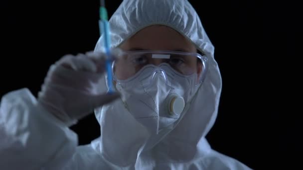 Фармаколог показывает шприц перед камерой на черном фоне, нелегальная лаборатория — стоковое видео