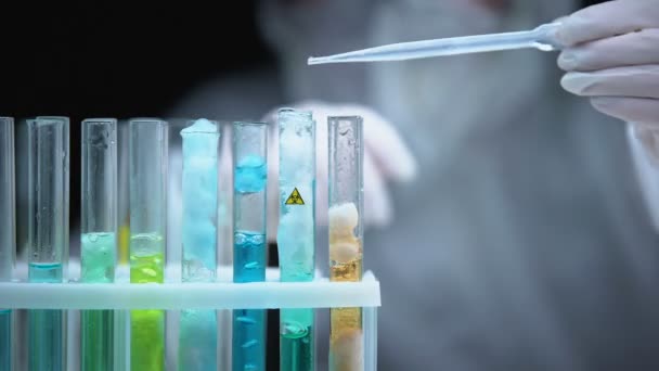 Лаборант наливает жидкость в пробирку с символом биологической опасности, современным оружием — стоковое видео