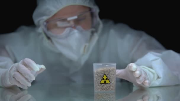 Ecologista cerrando frasco con semillas y signo de radiación, muestra de área contaminada — Vídeos de Stock