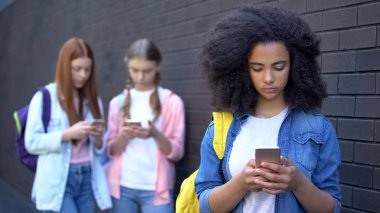Kız okul öğrencileri açık havada akıllı telefonlar kaydırma, gadget bağımlılığı, internet