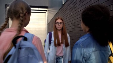 Şaşkın kızıl saçlı genç gözlük zalim sınıf arkadaşları önünde ayakta