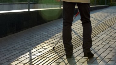 Görme engelliler için özel dokunsal kaldırımüzerinde baston yürüyüş görme engelli adam