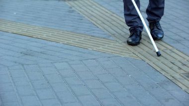 Blind man finds turn on tactile paving using walking stick, urban navigation clipart