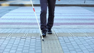 Visually impaired man using tactile tiles to navigate city, finishing crossroad clipart