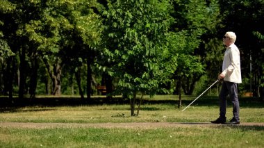 Kör emekli güvenli bir şekilde beyaz baston kullanarak gezinmek, parkta bağımsız yürüyüş