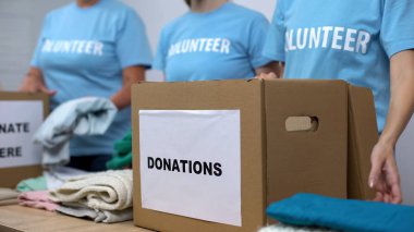 Social center volunteers putting clothes in donation boxes, altruism generosity clipart