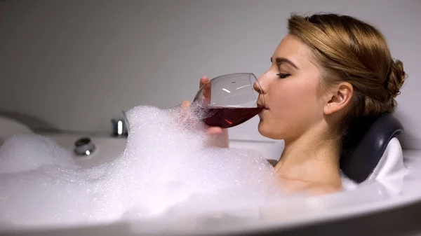 快乐的女人在浴缸里喝葡萄酒 泡泡泡泡 辛苦工作后放松 — 图库照片