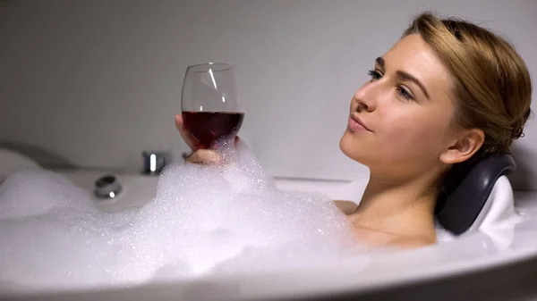 漂亮的女性拿着酒杯 在浴缸里用泡沫泡泡休息 家庭水疗 — 图库照片