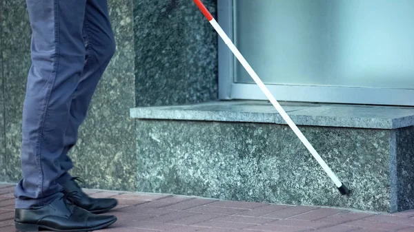 Blind man finding obstructions with cane, difficulties for handicapped in cities